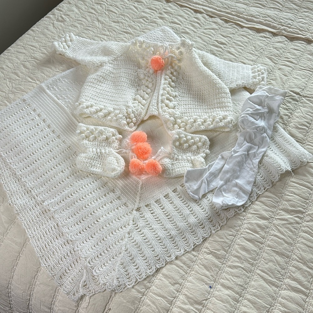 Newborn homemade sweater with orange pom-poms on sweater bootees vintage blanket